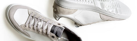 A pair of low-top Floris van Bommel sneakers in light grey and white, with one shoe shown from the side and the other from the sole view, on a plain white background.