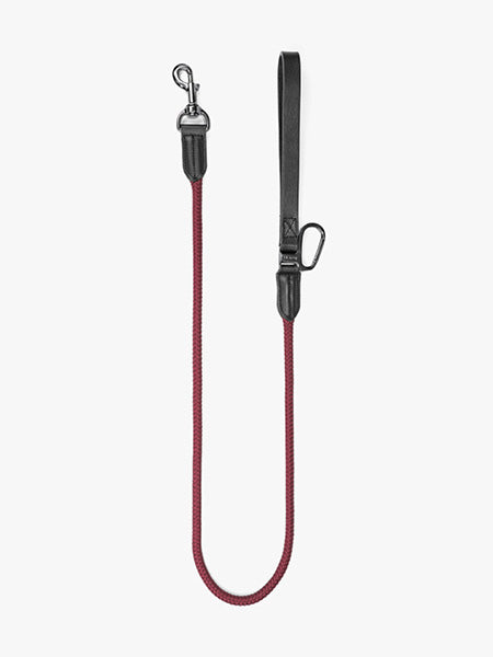 Dog leash Floris van Bommel. A red braided rope dog leash with black leather handle and silver metal hardware, shown against a plain light gray background.