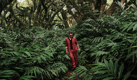 Floris van Bommel in a red suit walking through a dense forest