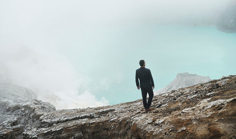 Floris van Bommel in a suit walking on a mountain ridge with a misty landscape
